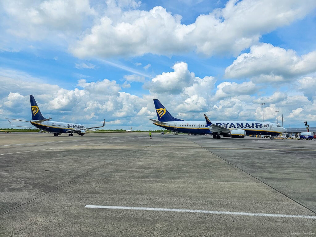 Two Ryanair airplanes are parked on the tarmac under a cloudy sky at Treviso Airport. This image highlights the travel route from Treviso Airport to Trieste, Italy cruise port, emphasizing the convenience of reaching the cruise terminal in Trieste, Italy.