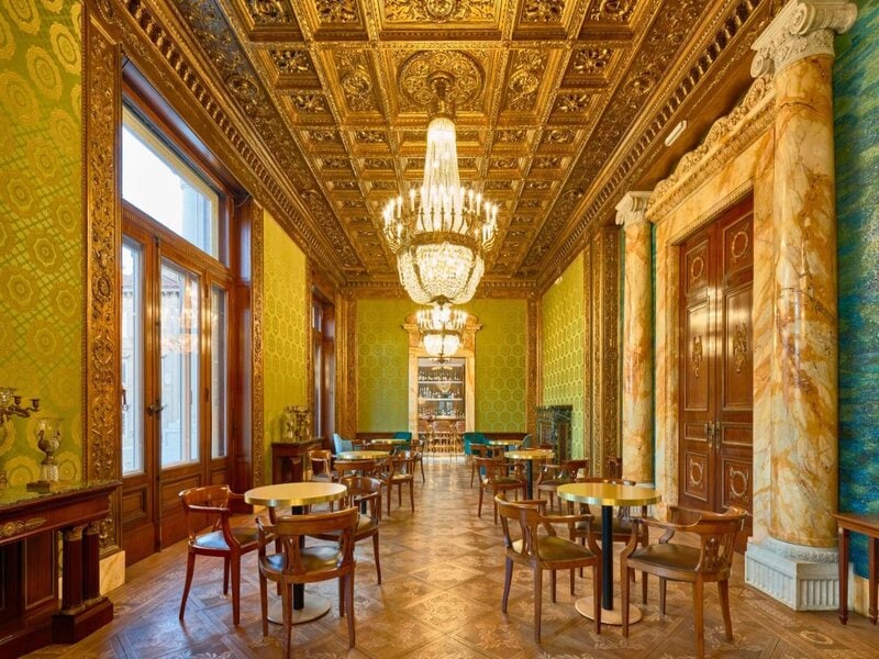 "Luxurious, ornately decorated dining area with chandeliers inside the DoubleTree by Hilton Trieste, showcasing the elegance of Hilton hotels