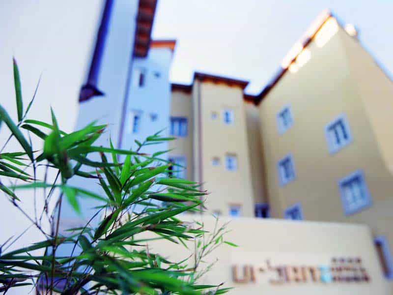 "View of the Trieste Urban Hotel Design building with lush greenery in the foreground,
