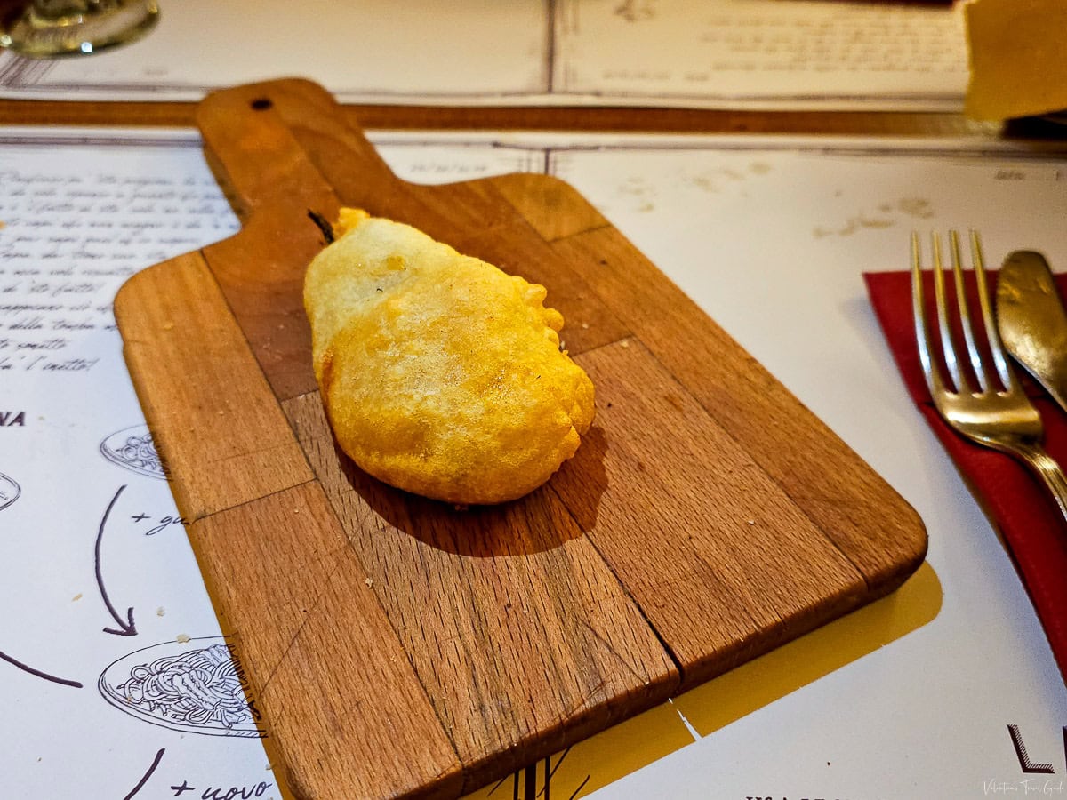 Golden battered zucchini flower served on a wooden board at a popular restaurant in Testaccio, Rome, highlighting traditional Italian flavors. in one of the best Roman restaurants in Rome 