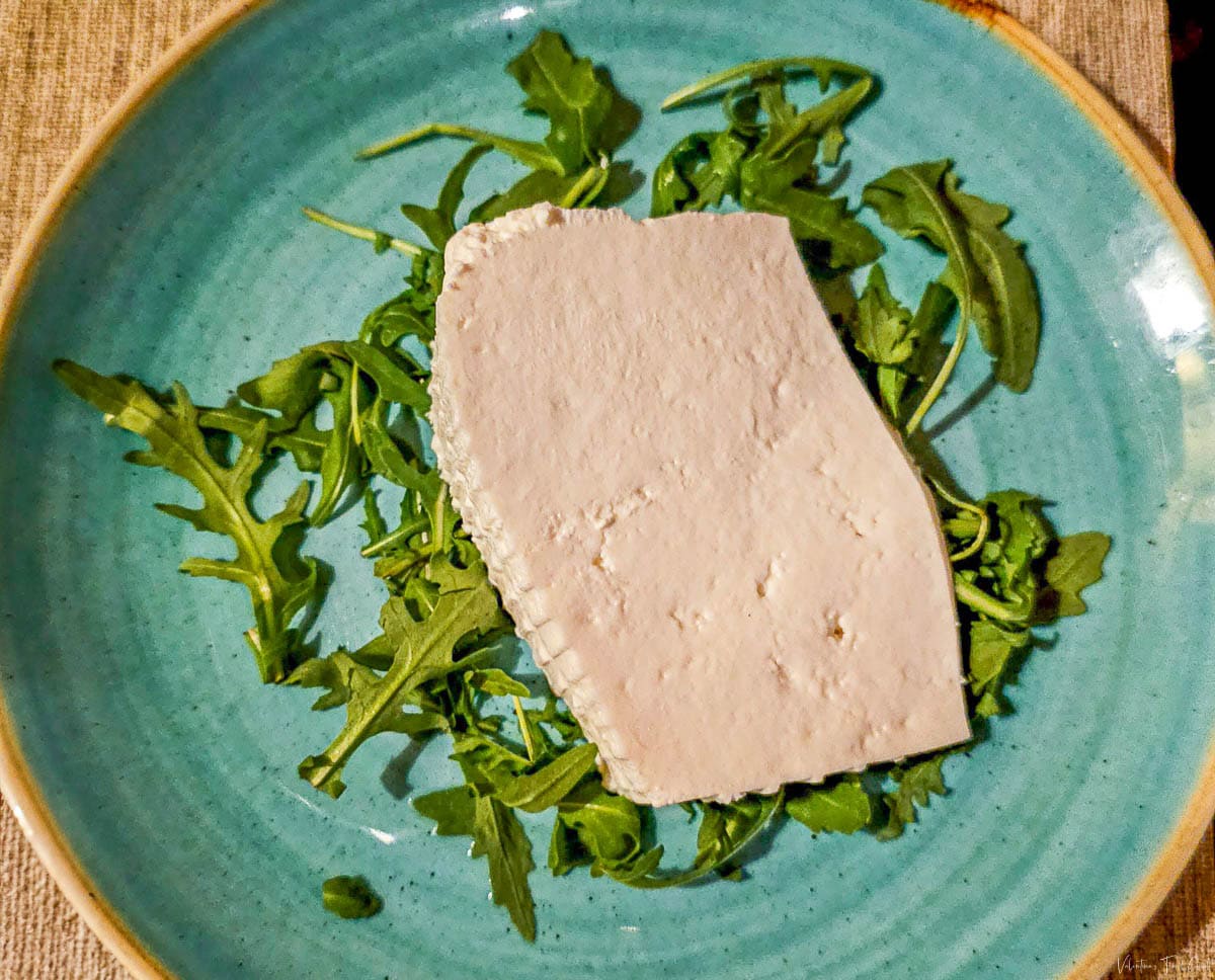 Fresh Italian sheep ricotta served on a bed of arugula, elegantly plated on a turquoise dish, highlighting the quality and presentation found at the best restaurants that Rome has to offer, perfect for the best dinner experience.