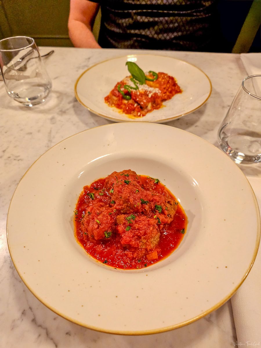 Delicious Italian meatballs in a rich tomato sauce served at a table with another classic pasta dish in the background, offering a taste of authentic cuisine at one of the best restaurants near Vatican City Rome