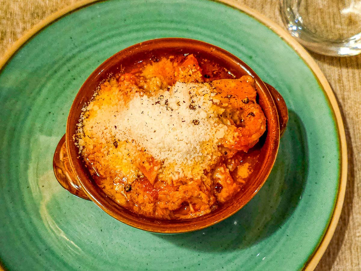 Traditional Roman tripe dish topped with grated Pecorino Romano cheese, served in a rustic terracotta bowl, highlighting the authentic flavors of Monti neighborhood