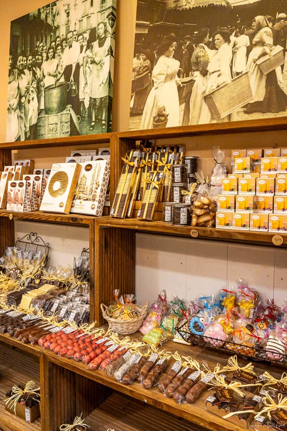 Interior of a charming Barcelona sweets and souvenir shop with wooden shelves displaying artisanal chocolates, candies, cookies, and locally packaged treats, all tied with decorative ribbons. While not located directly at the terminal, shops like this are often found near Barcelona cruise port facilities, offering travelers unique local gifts and snacks before or after their voyage.